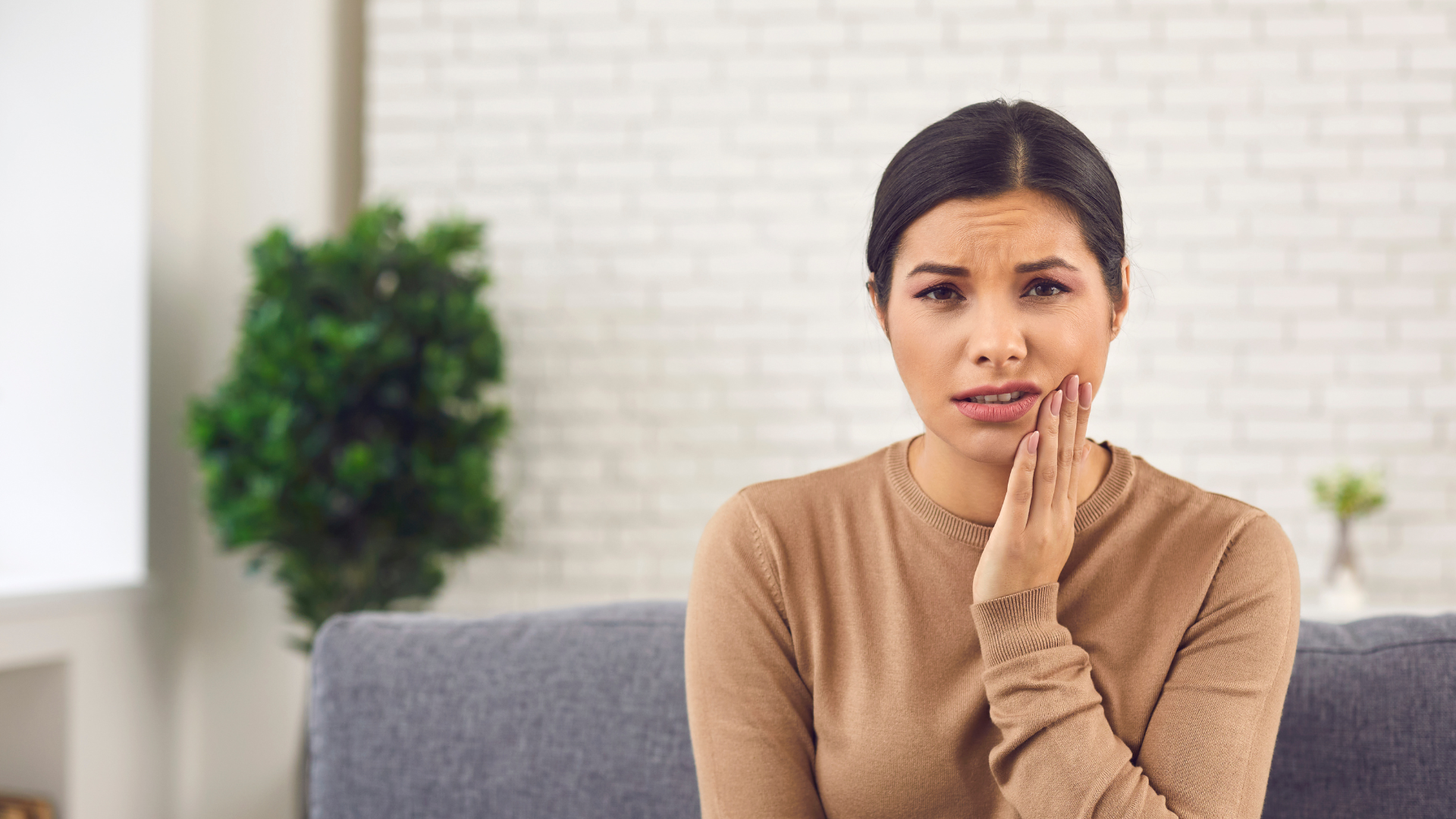 Female looking at the camera holding her mouth in pain